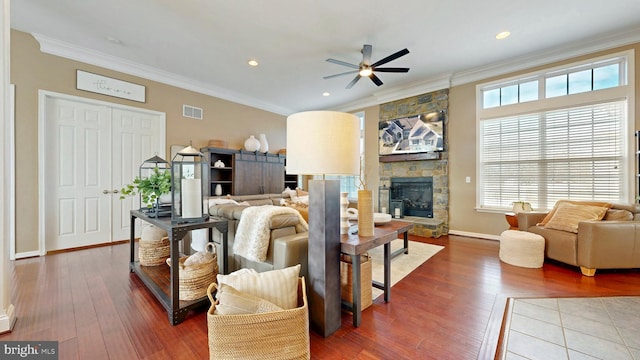 living area featuring visible vents, crown molding, baseboards, a fireplace, and wood-type flooring