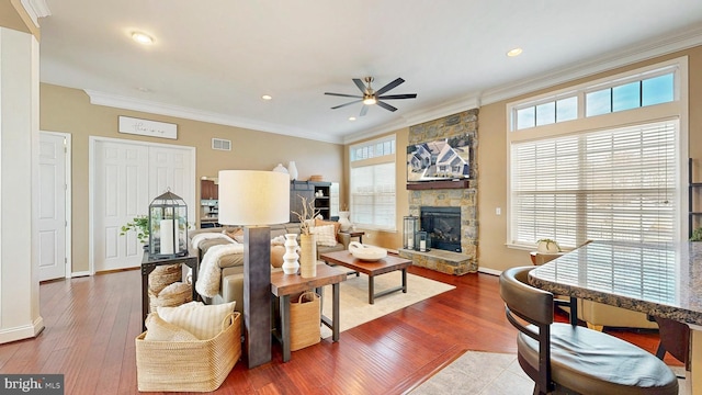 living room featuring baseboards, a fireplace, wood finished floors, and crown molding