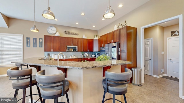 kitchen featuring tasteful backsplash, baseboards, a kitchen bar, hanging light fixtures, and stainless steel appliances