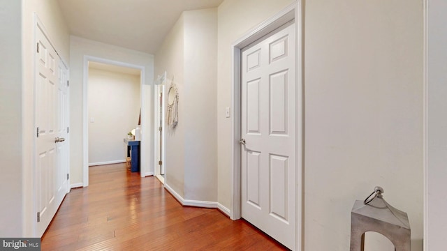 corridor featuring baseboards and wood finished floors