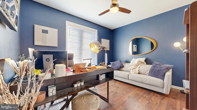 living area with baseboards, a ceiling fan, and hardwood / wood-style flooring