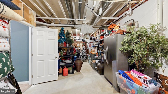 unfinished basement with stainless steel refrigerator with ice dispenser