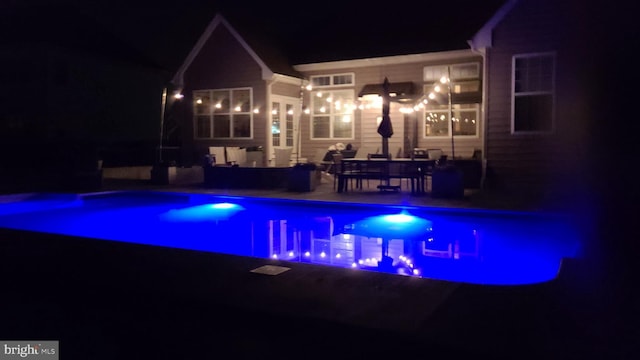 pool at twilight with a patio and an outdoor pool