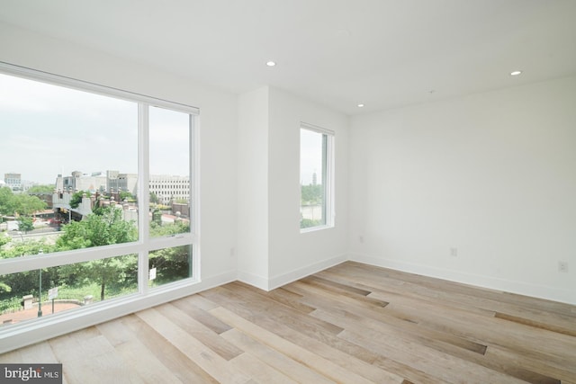 empty room featuring a view of city, baseboards, wood finished floors, and recessed lighting