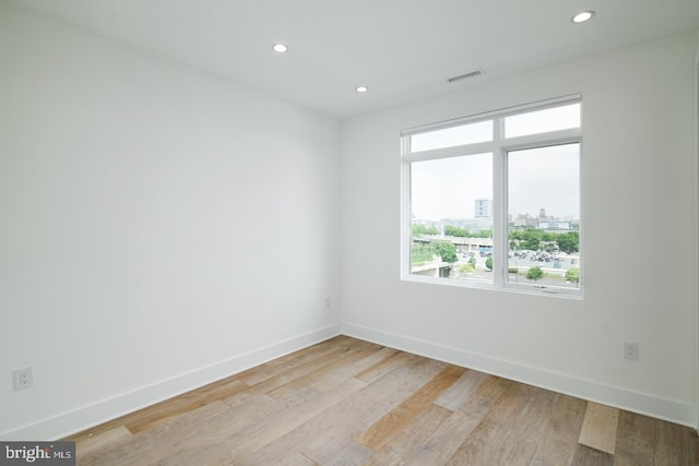 spare room featuring light wood finished floors, baseboards, visible vents, and recessed lighting