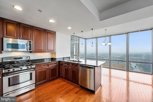 kitchen featuring a sink, dark stone counters, light wood-style floors, and appliances with stainless steel finishes