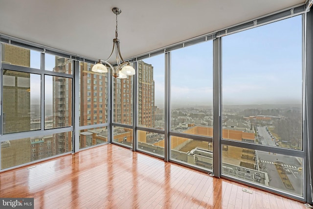 unfurnished sunroom with a view of city, plenty of natural light, and a chandelier