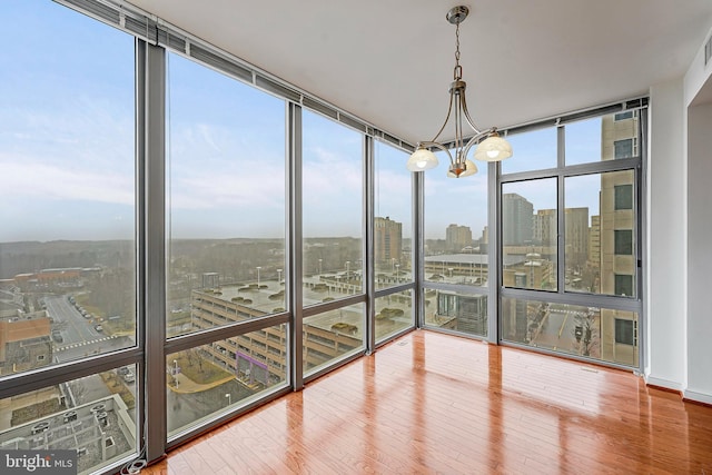 unfurnished sunroom featuring a city view, an inviting chandelier, and visible vents