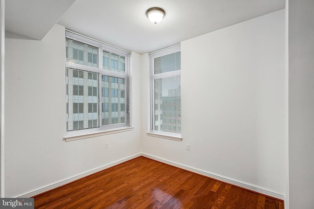 unfurnished room with baseboards and wood finished floors