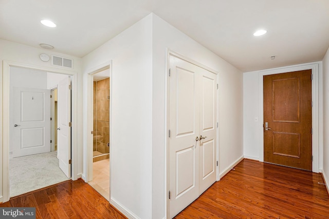 corridor featuring visible vents, recessed lighting, baseboards, and wood finished floors