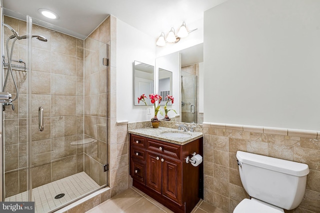 full bath with vanity, a shower stall, wainscoting, tile walls, and toilet