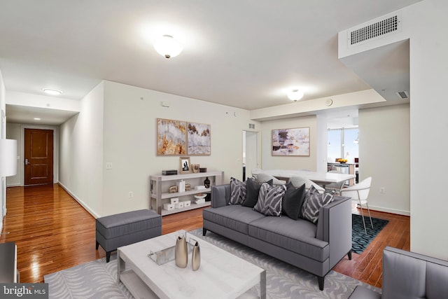 living area with visible vents, baseboards, and wood finished floors