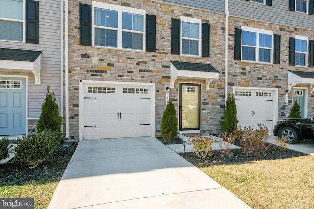 multi unit property featuring concrete driveway, stone siding, and an attached garage