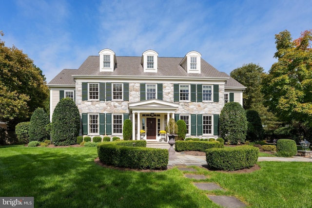 colonial-style house with stone siding and a front lawn