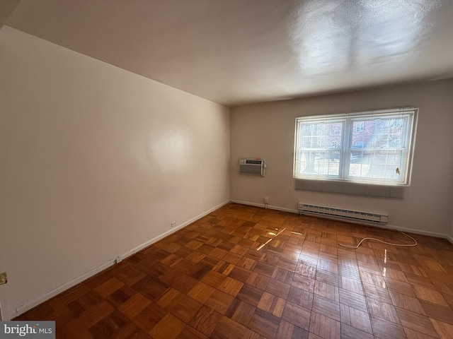 spare room with an AC wall unit, baseboard heating, and baseboards