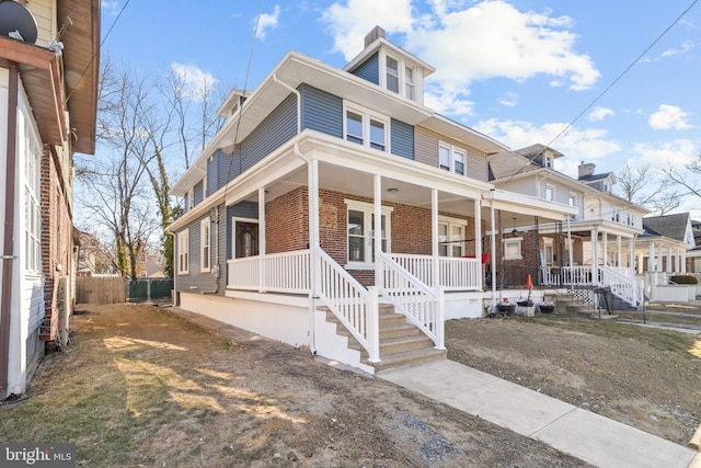 traditional style home with covered porch, brick siding, and fence