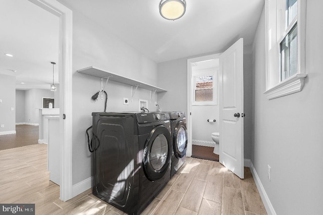 laundry room featuring laundry area, wood finish floors, washing machine and dryer, and baseboards