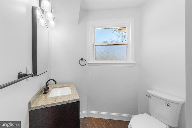 bathroom featuring toilet, baseboards, wood finished floors, and vanity