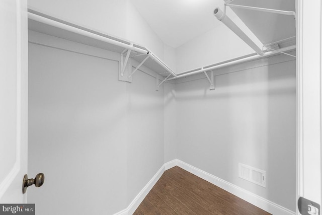 walk in closet with dark wood finished floors and visible vents