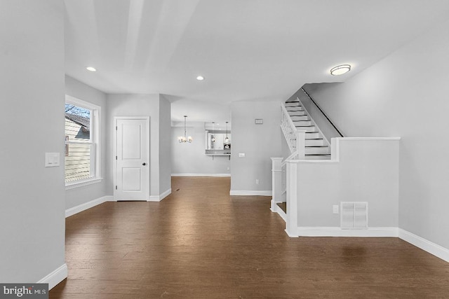 interior space featuring dark wood-style floors, a notable chandelier, visible vents, and baseboards