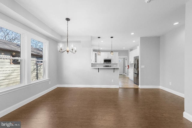 unfurnished living room featuring baseboards, a chandelier, wood finished floors, and recessed lighting