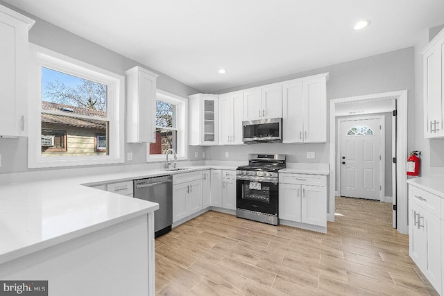 kitchen with light countertops, appliances with stainless steel finishes, light wood-type flooring, and white cabinets