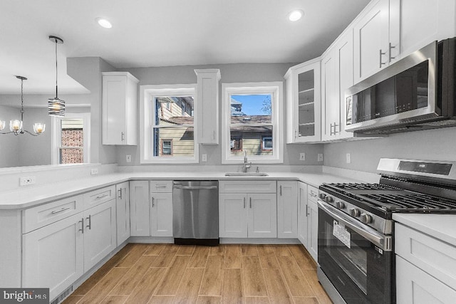 kitchen featuring light wood-style flooring, recessed lighting, stainless steel appliances, a sink, and white cabinetry