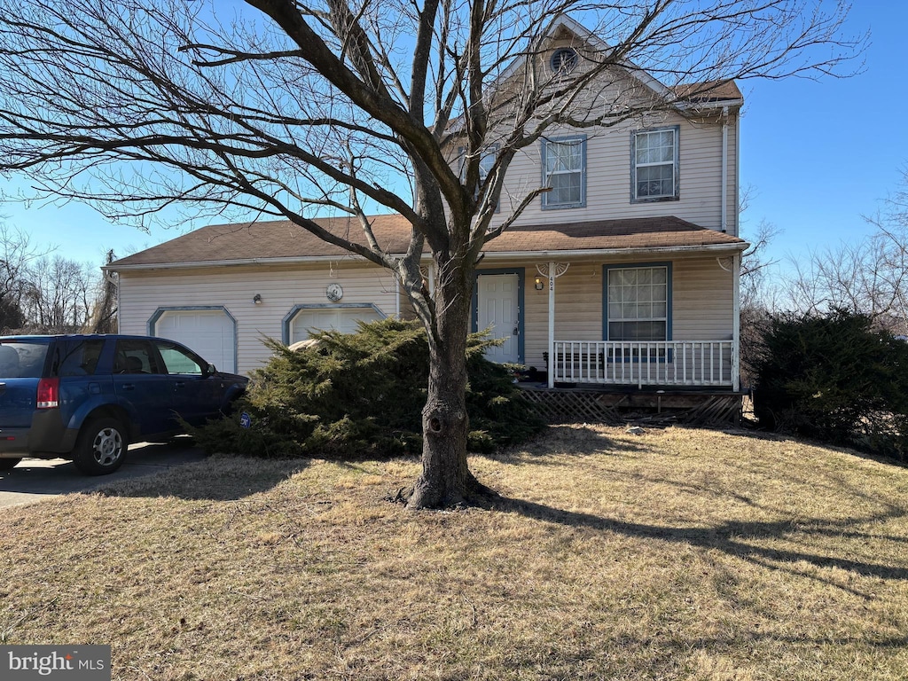 traditional-style house featuring a garage, covered porch, and a front yard