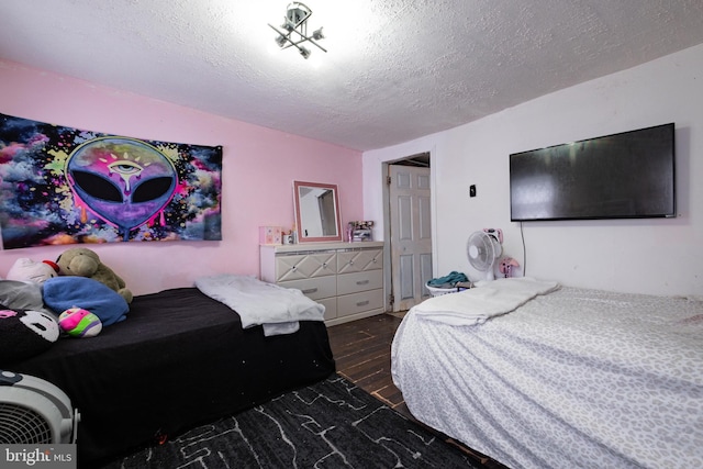 bedroom with a textured ceiling and wood finished floors