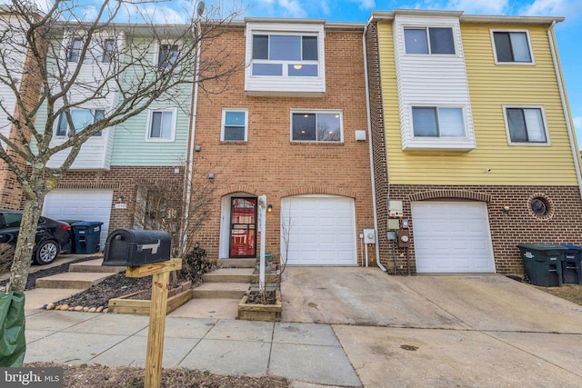 townhome / multi-family property featuring a garage, driveway, and brick siding