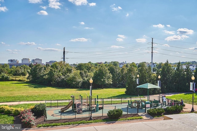 view of home's community featuring playground community, a lawn, and fence