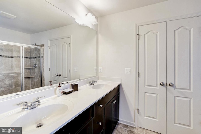 full bath with double vanity, a stall shower, a sink, and baseboards