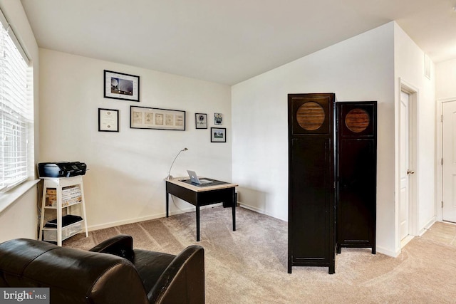 office space featuring light colored carpet, vaulted ceiling, and baseboards