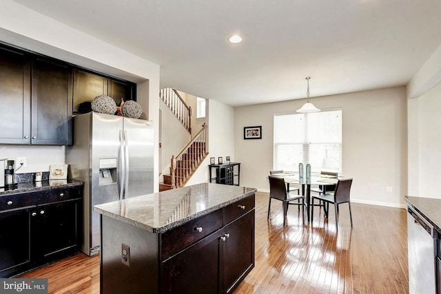 kitchen featuring appliances with stainless steel finishes, dark stone counters, a center island, and light wood-style floors