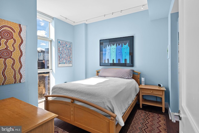 bedroom with dark wood finished floors and track lighting