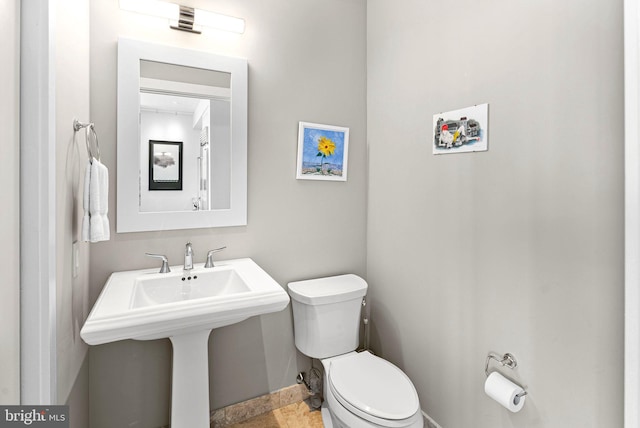 bathroom with stone finish floor, a sink, and toilet