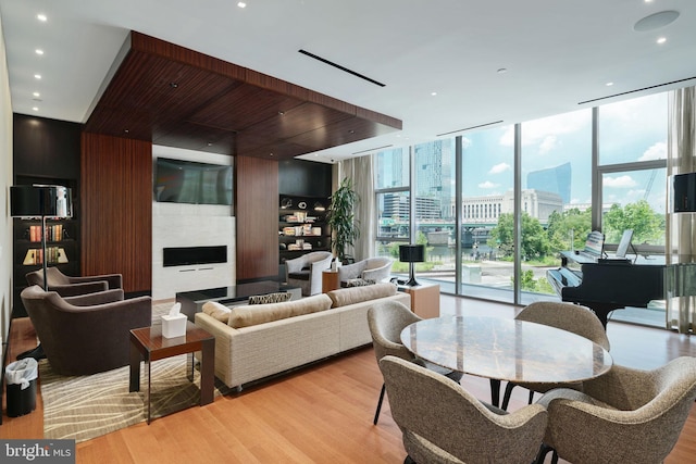 living area featuring expansive windows, a large fireplace, light wood finished floors, and recessed lighting