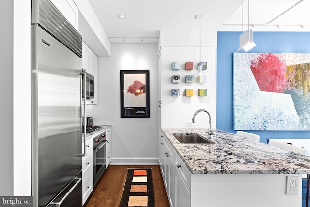 kitchen with a peninsula, appliances with stainless steel finishes, white cabinets, and a sink