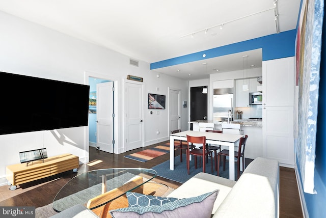 living area with track lighting, visible vents, dark wood finished floors, and baseboards