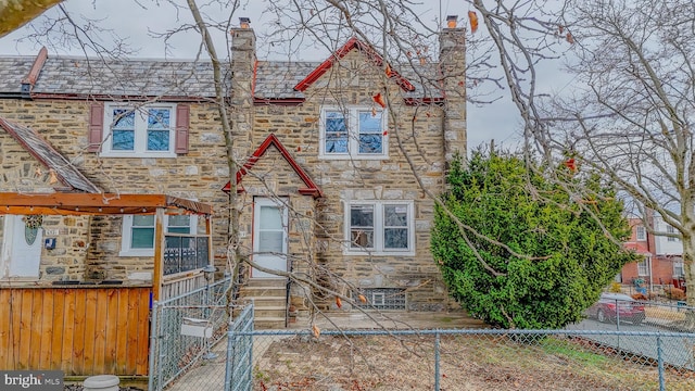 view of front of home featuring a fenced front yard, a high end roof, and stone siding