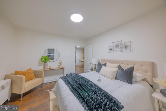 bedroom with radiator and wood finished floors