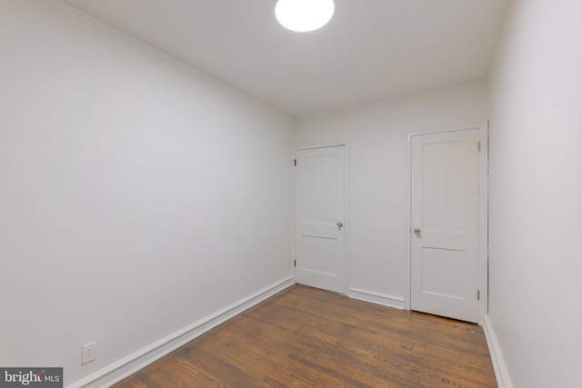 unfurnished room featuring baseboards and dark wood finished floors