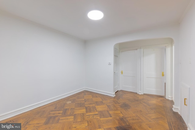 unfurnished room with baseboards and arched walkways