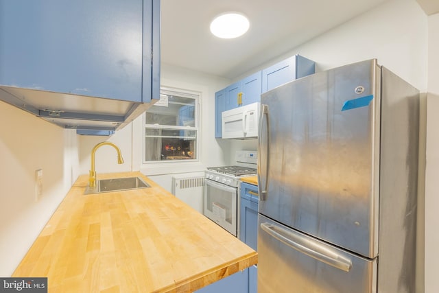 kitchen with blue cabinetry, radiator, butcher block counters, a sink, and white appliances