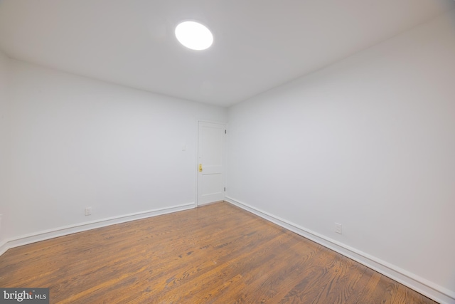 spare room featuring baseboards and wood finished floors