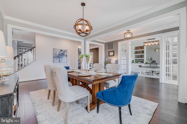 dining space with a chandelier, hardwood / wood-style flooring, built in features, ornamental molding, and french doors