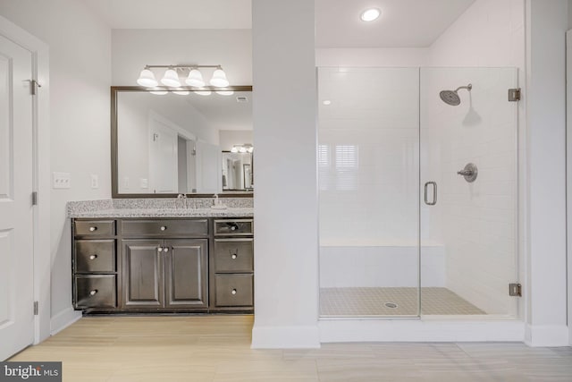 full bath with a stall shower, wood finished floors, and vanity