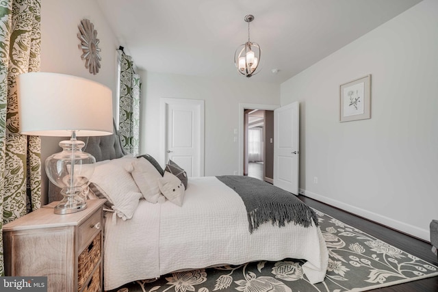 bedroom featuring an inviting chandelier, baseboards, and wood finished floors