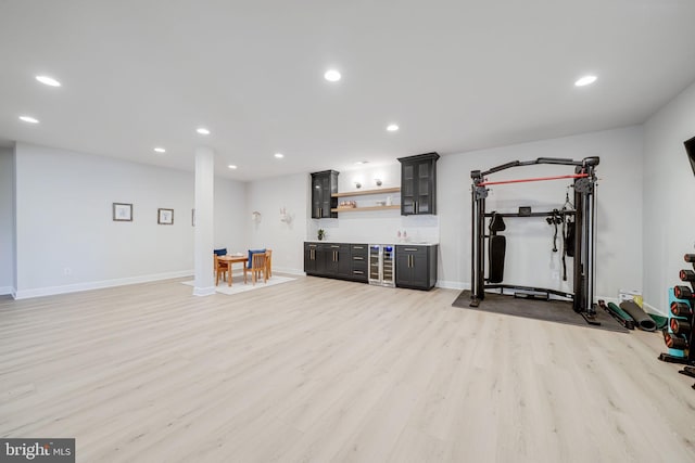 workout room featuring baseboards, light wood finished floors, indoor bar, and recessed lighting