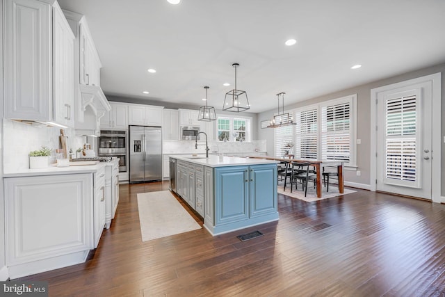 kitchen with dark wood-style floors, stainless steel appliances, blue cabinetry, and white cabinets